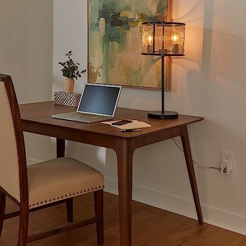 Minimalist home office with wooden desk, laptop, lamp, and chair.